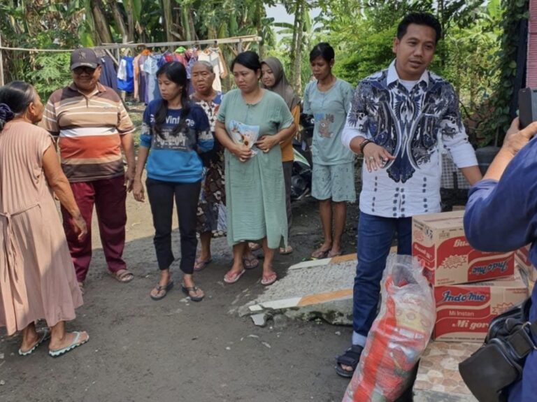 Kepala Desa Kalisampurno, Dedi Purwandoyo, saat menyerahkan bansos kepada warga terdampak banjir .
